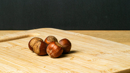 Group of hazelnuts on a wooden board with a black backgroundの写真素材