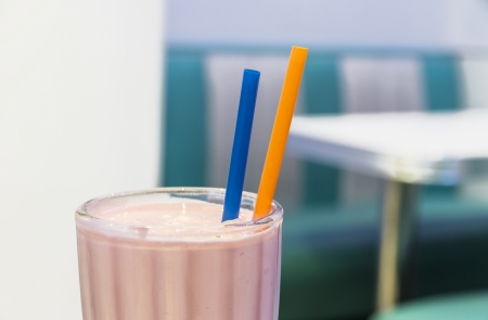 A strawberry milkshake glass with drinking straws in a tipical burguer barの写真素材
