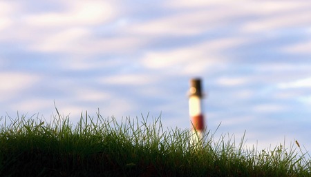 Factory chimney behind green lawn with cloudy skyの写真素材