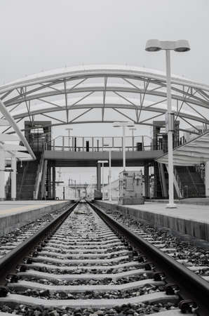 View from between the rails looking up at the train platform and pedestrian overpass.のeditorial素材