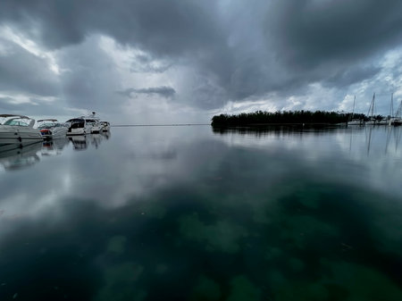 Boats moored in the harbor under a dramatic sky with cloudsの写真素材