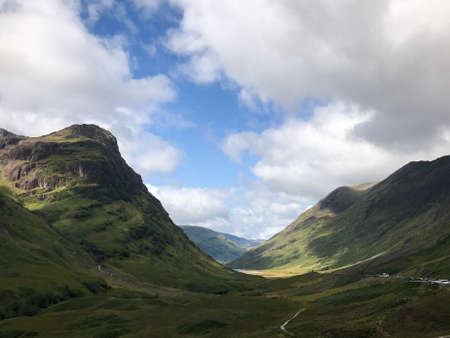 The sun is shining on the green valley of the Glencoe mountains in the Scottish highlands in Julyの写真素材