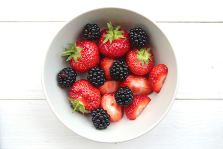 a bowl of fresh and delicate strawberries and blackberriesの写真素材