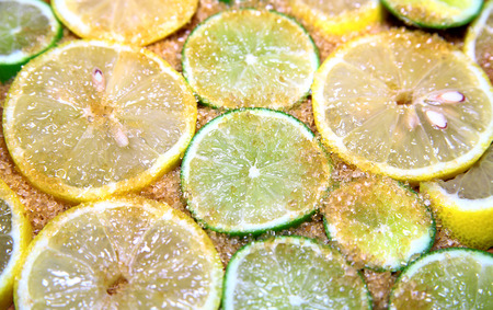 view on slices of limes and lemons mixed with cane sugar placed flat on the groundの写真素材