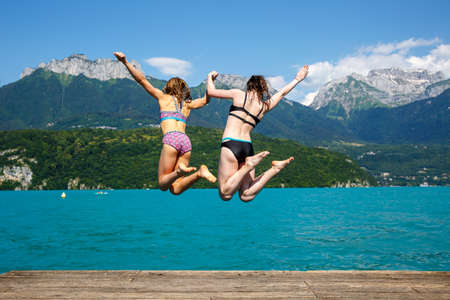 Two teen girls jumping into Lake Annecy at Plages de Saint Jorioz - Franceの写真素材