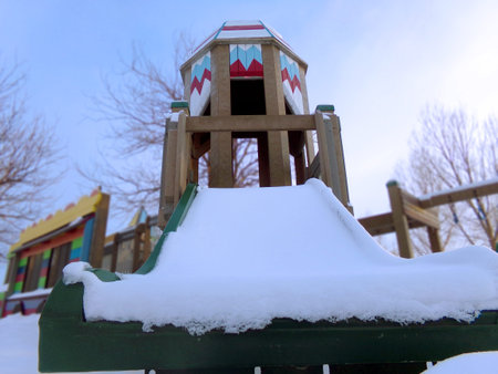A snowed over slide in the middle of a playground during winter located in Wyoming.の写真素材