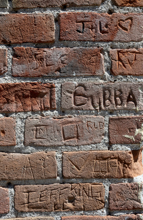 Red brick wall with multiple names embedded in the brickの写真素材