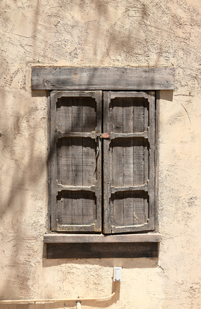 Old wood framed shuttered window with a lock, set in an adobe wallの写真素材