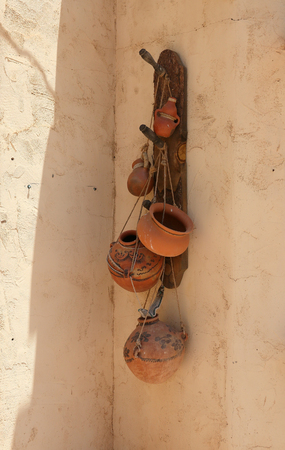 Terra cotta pots hanging on the shady side of an adobe wallの写真素材