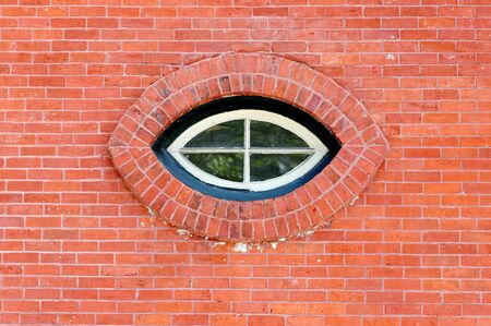Cat eye shaped window in a red brick wallの写真素材