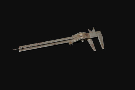 An older well used vernier caliper isolated on a dark background