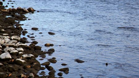 Rivers edge with rocks, ripples and blue water in the Bow Riverの写真素材