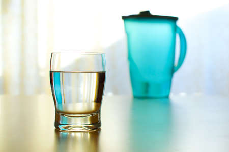 Cool and colorful glass of refreshing water with a full pitcher in the backgroundの写真素材