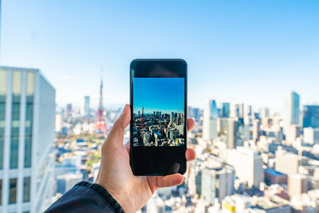 hand holding a phone on Tokyo cityscape - modern aerial view with Roppongi and Minato wards.
