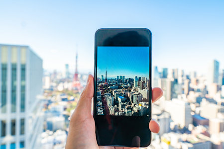 hand holding a phone on Tokyo cityscape - modern aerial view with Roppongi and Minato wards.のeditorial素材