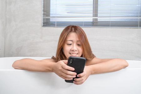 Young and beautiful girl using phone relaxing in the retro bath indoors