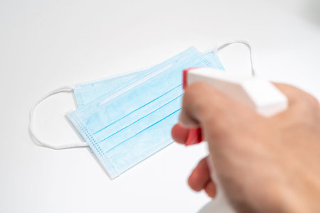 Protective face mask and sanitizer gel dispenser on white background