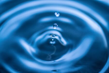 water drop splash in a glass blue coloredの写真素材