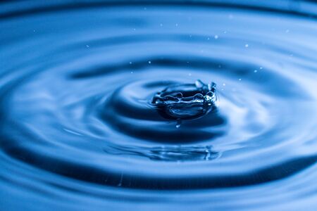 water drop splash in a glass blue coloredの写真素材