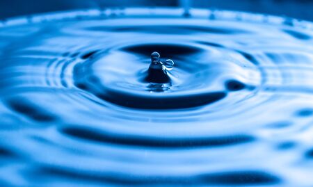 water drop splash in a glass blue coloredの写真素材