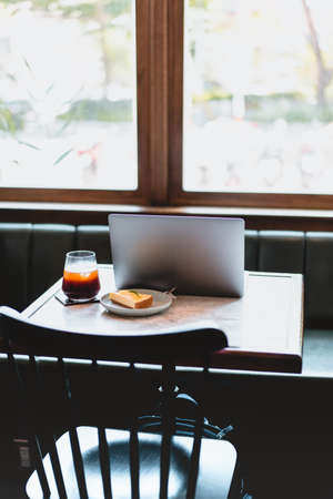 laptop computer, lemon Cheesecake and a cup of coffee in modern restaurantの写真素材