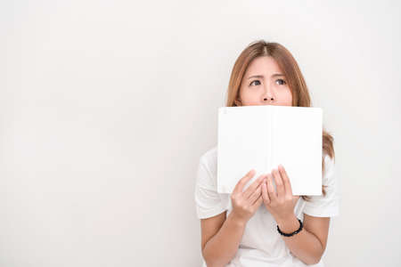 Young attractive asian student holding books in her arm on white background. School girl with a books to read for homework.の写真素材
