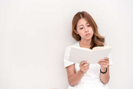 Young attractive asian student holding books in her arm on white background. School girl with a books to read for homework.の写真素材