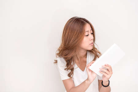 Young attractive asian student holding books in her arm on white background. School girl with a books to read for homework.の写真素材