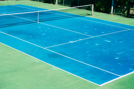 Deserted tennis court with greentrees in background in a public park on a sunny summer morningの写真素材