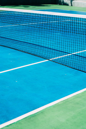Deserted tennis court with greentrees in background in a public park on a sunny summer morningの写真素材