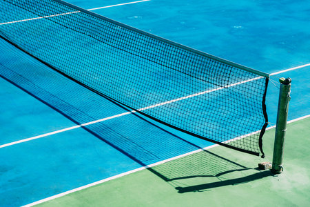 Deserted tennis court with greentrees in background in a public park on a sunny summer morningの写真素材