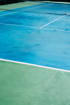 Deserted tennis court with greentrees in background in a public park on a sunny summer morningの写真素材