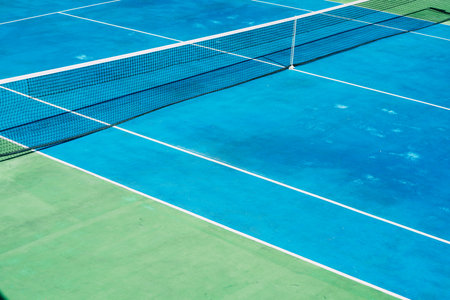 Deserted tennis court with greentrees in background in a public park on a sunny summer morningの写真素材