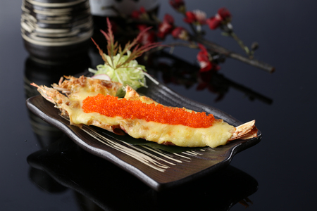 Grilled cheese shrimp with crab roe in a dark plateの写真素材