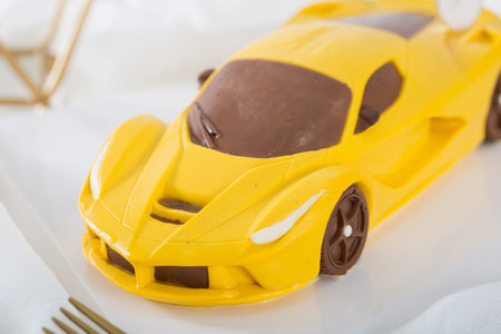 Delicate yellow sports car shaped cake in a white dishの写真素材