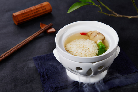 Chicken soup with matsutake and tofu in a white potの写真素材