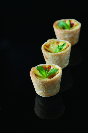 Three golden portuguese egg tart pastry with mint leafの写真素材