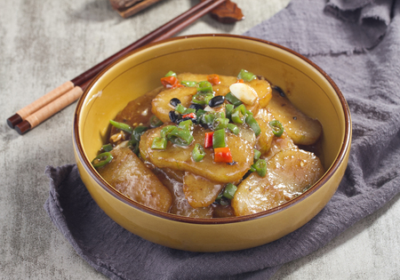 Braised potato chips with red and green pepper in a ceramic dishの写真素材