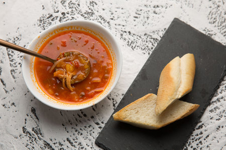 Spicy chicken soup and bread on table