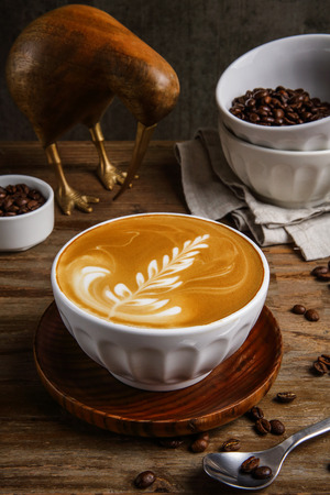 Latte art in a ceramic cup with coffee beansの写真素材