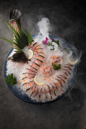 Fresh fish slices with ice in the black ceramic dishの写真素材