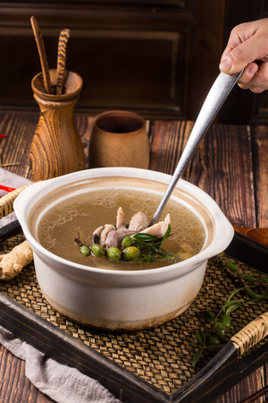 Stewed pig intestines with olives soup in a white ceramic potの写真素材