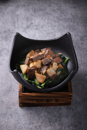 Fried beef with soy sauce in a black ceramic dishの写真素材