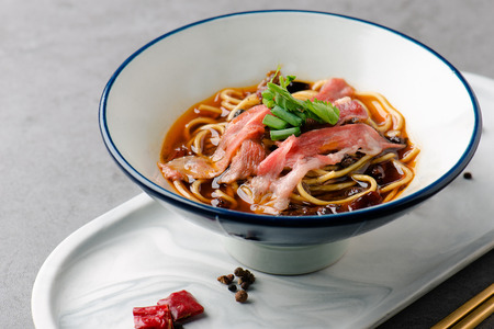 Spicy beef noodles in a white ceramic dishの写真素材