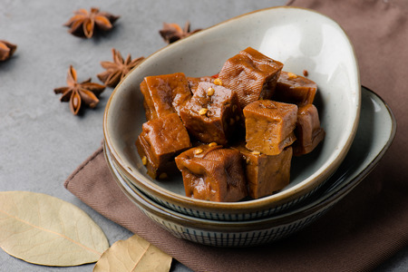 Star aniseed and dried bean curds in a white ceramic dishの写真素材