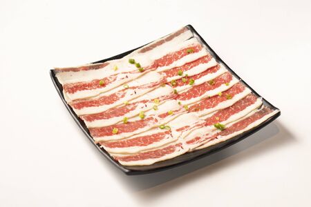 Fresh cut marbled sliced beef in a black ceramic dishの写真素材