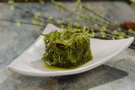 Cold seaweed salad on white triangle ceramic dishの写真素材