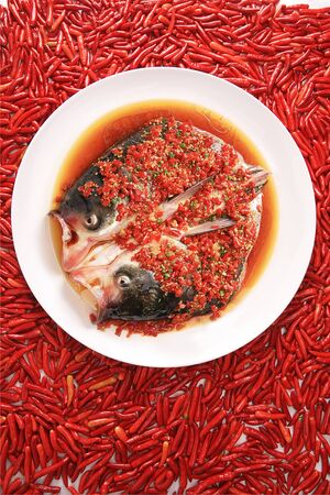 Steamed fish head with chopped chili in a white ceramic dishの写真素材
