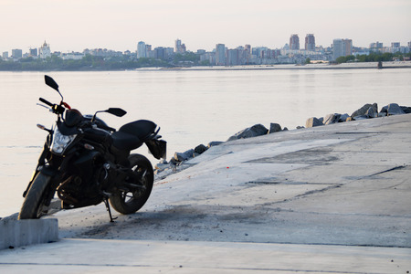 black motorcycle beside the riverside landscape.の写真素材