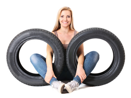 Young sexy girl sitting near the car wheels, isolated on white.の写真素材